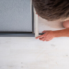 Installing a plinth in the room, measuring the required length using a square and a ruler, a gray...
