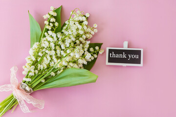 Beautiful lily of the valley  flowers and thank you message on pink  background  .Thank you card...