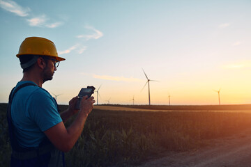 Engineer mechanic using drone for inspection in a windmill farm park.