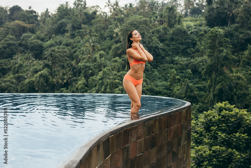 Wall mural Young woman wearing bikini standing in swimming pool