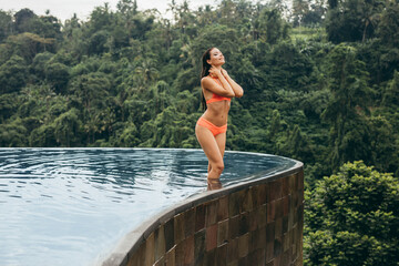 Young woman wearing bikini standing in swimming pool