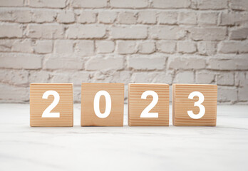 Plan to 2023. Wooden cubes with the letters 2023 with a white brick wall background