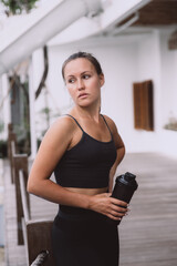 Fototapeta na wymiar Tired woman standing and resting after workout with bottle of water