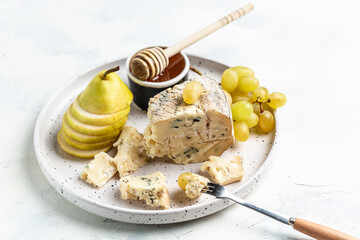 Piece of Blue cheese pear, grapes and honey on a light background. French cuisine, Delicious food wine snacks assorted. place for text, top view