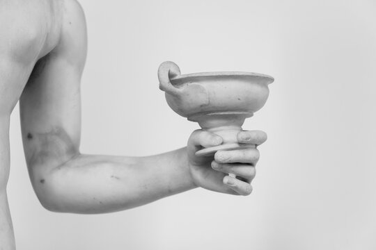 Black and white photo showing in hand of ancient roman statue holding a cup