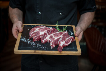 Raw steak with bone served on board