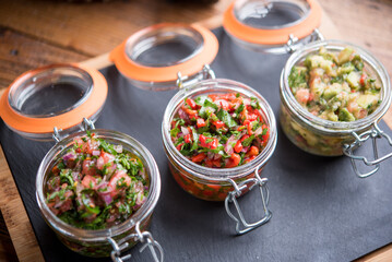 Assorted chopped vegetables served in jars on stone board