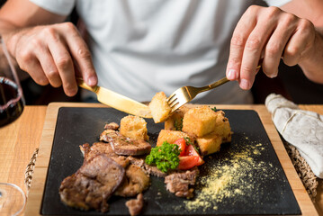 Man eating delicious beef dish complimented with red wine