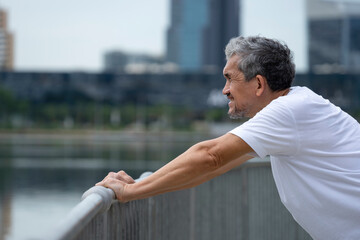 Fototapeta premium happy senior man with grey hair warming up before workout in the city park. concept for elderly people lifestyle, health care, wellbeing