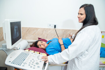 Indian Gynecologist doctor wearing does ultrasound, sonogram screening or Scanning Belly of...