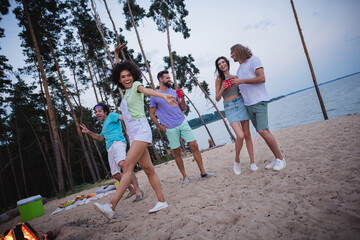 Full length photo of millennial guys ladies drink beer dance wear casual cloth by the beach