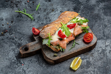 Sandwiches with homemade ciabatta bread, salted salmon fish, parmesan cheese, capers, cherry tomatoes and arugula, Restaurant menu, dieting, cookbook recipe top view