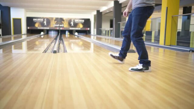 4K man throwing bowling ball at bowling alley striking down two last pins. Entertainment, sports, spending free time concept.