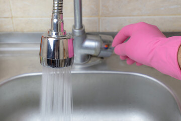 the man turns on the water in the sink in the kitchen