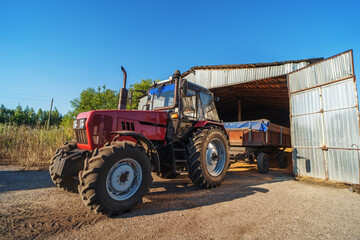 Tractor unloading grain harvest to granary storage on farm.