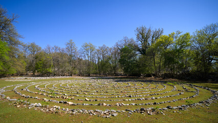 Labyrinth made of white stones on a green meadow near Beli on a sunny day in spring