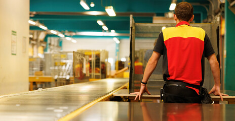 A man is waiting for the packages on the conveyor belt in the warehouse