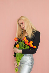 Fashion blonde woman holding red tulips in her hands