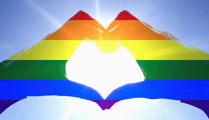 Hands raised up, creating the heart shape (universal symbol of love), colored with the stripes of the rainbow flag. Silhouette over a clean sky with a shiny sun.

