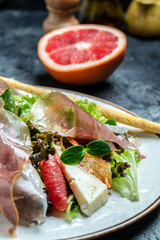 Prosciutto crudo ham salad with brie camembert cheese and grapefruit, salad mix. Restaurant menu, dieting, cookbook recipe