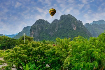 Fotobehang Hot Air Balloon over Vang Vieng Laos a beautiful city on the river with huge rising mountains and slow flowing river.  © Elias Bitar
