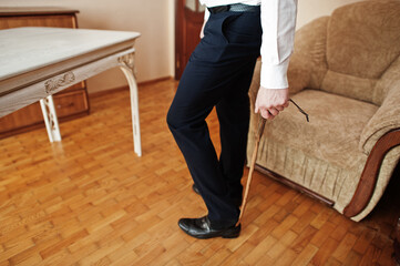 Man puts on classic black shoes with a wooden shoe spoon.