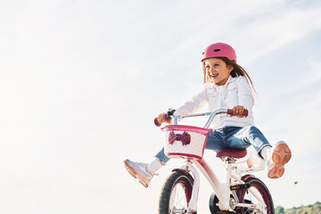 Fototapeta na wymiar Active weekend time spending. Happy little girl riding a bicycle outdoors in summer