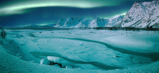 Fototapeta na wymiar Northern lights (Aurora borealis) in the sky over snow covered mountains range and river. Fantastic nature scenery. Wonderful winter landscape. Lofoten islands. Norway. Christmas travelling concept