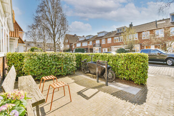 Neat paved patio with sitting area and small garden near wooden fence - obrazy, fototapety, plakaty