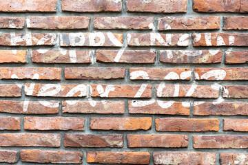 Graffiti with white ink wishing happy new year 2023 on a brick wall.