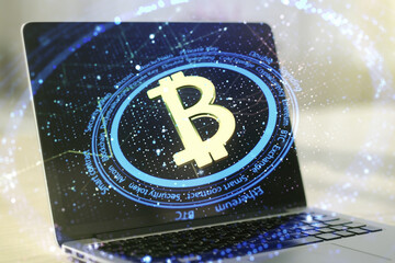 Double exposure of creative Bitcoin symbol hologram with computer on background. Mining and blockchain concept
