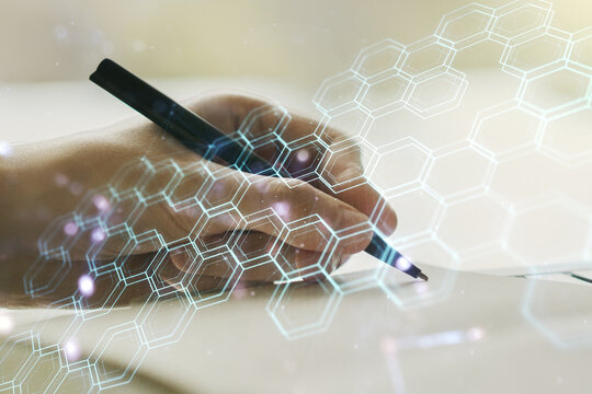 Creative concept of wireless technology with hexagon hologram and man hand writing in notebook on background. Big data and database concept. Multiexposure