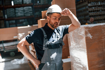 Tired employee in uniform is working in the dark storage