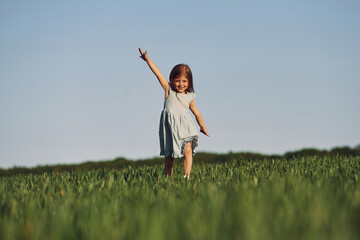 Naklejka na ściany i meble Enjoying nature. Happy girl have a walk outdoors on the field at summer