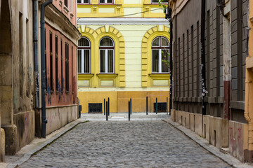 Fototapeta na wymiar Old town avenue with nobody on the cobblestone road and weathered buildings. Narrow path with cobble in old urban region