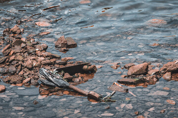 Electric rental scooter found in water in an urban area. Electronic toxic waste of water pollution concept