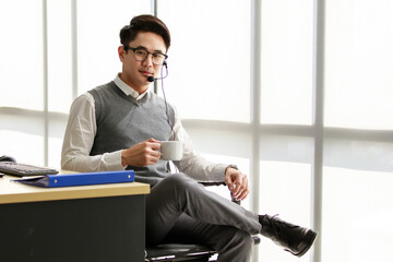 A handsome young Asian call center officer with a dignified personality looks like an executive or...