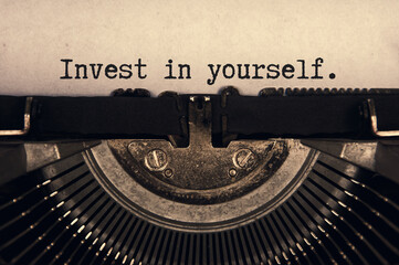 Invest in yourself text typed on an old vintage typewriter in black and white