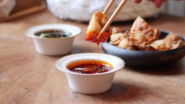 Client dipping a fried dumpling in a spicy sauce