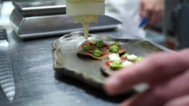 Chef plates a Mexican inspired dish in a restaurant's kitchen 