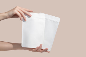 Woman's hands hold cardboard packages for tea or snacks on a beige background. Tea branding and...