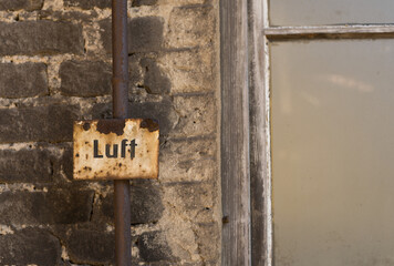 Industrial background rusty enamel sign with inscription air in front of dirty wall with window in detail heavy industry
