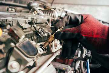 A auto mechanic is installing automobile iridium spark plugs into the ignition socket of the engine...