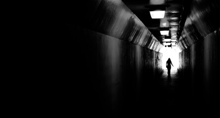 Fototapeta premium Person walking through tunnel towards light at end. Accomplishing goal or leaving darknenss for light.