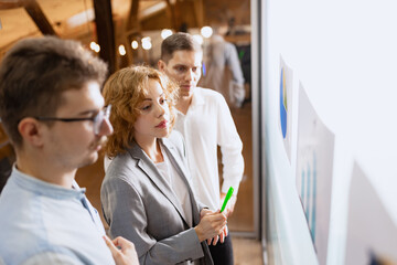 Group of happy, motivated young people discussing plans and projects. Coworkers working at office, indoors. Concept of business, teambuilding