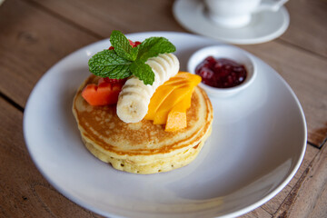 Pancakes with banana, mango, mint and strawberry jam for a breakfast.