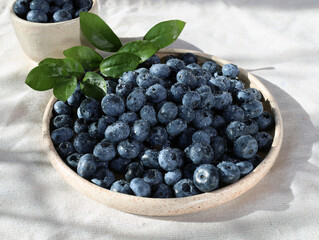 Blueberries on a plate, hard light. Fresh blueberries with water drops. Blue berries on a plate on the tablecloth.