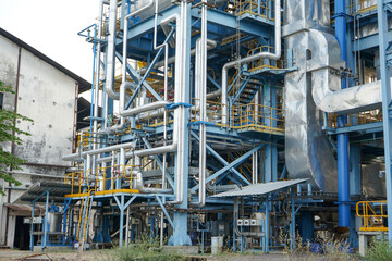 Fototapeta na wymiar Modern factory with many pipes and tanks with stainless steel construction. This factory can produce various kinds of processed products such as oil. 