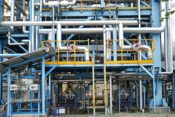 Modern factory with many pipes and tanks with stainless steel construction. This factory can...