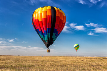 two balloons fly over the endless steppe low above the ground, choosing a place to land